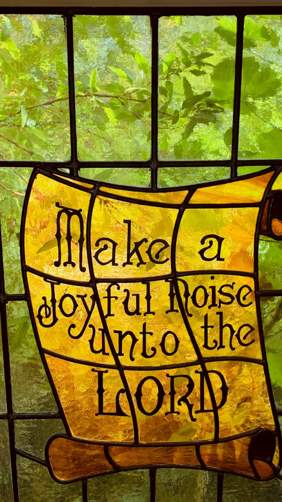 Stained glass with message "Make a Joyful noise unto the Lord"